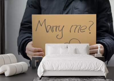 A woman holds a paper with the inscription “Marry me?